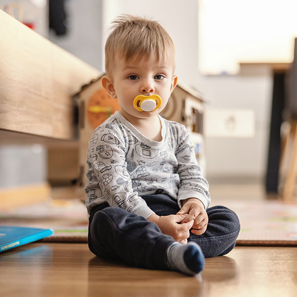 Young boy sitting on the floor with a pacifier